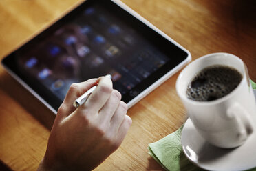 Cropped image of hand holding stylus and using digital tablet on table - CAVF18712