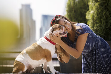 Lächelnde Frau mit Bulldogge an einem sonnigen Tag - CAVF18750