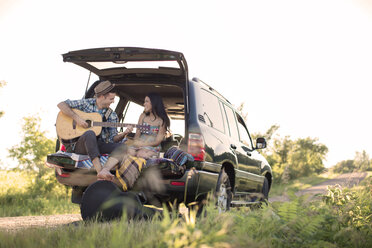 Mann spielt Gitarre für Freundin im Auto sitzend - CAVF18842