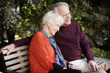 Happy senior couple sitting on park bench - CAVF18854