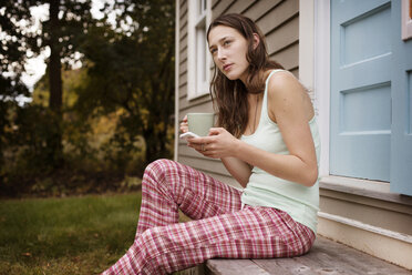 Young woman standing wearing bra and pyjama pants looking down stock photo