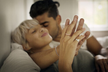 Zärtlicher junger Mann küsst Frau und hält Hand im Schlafzimmer - CAVF18890