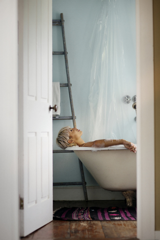 Seitenansicht einer Frau, die sich zu Hause in der Badewanne entspannt, lizenzfreies Stockfoto