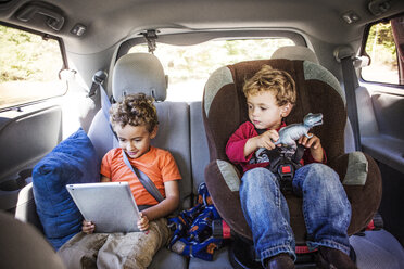 Siblings looking at tablet computer in car - CAVF18927