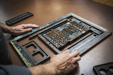 Man assembling letterpress on workbench in workshop - CAVF18962