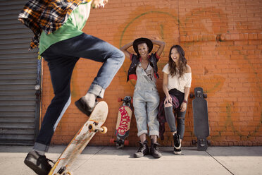 Freundinnen beobachten einen Mann bei einem Skateboard-Stunt - CAVF18993