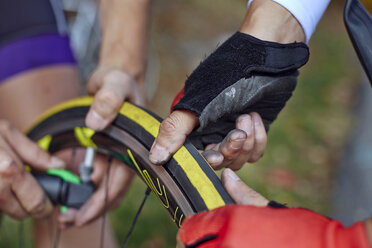 Close-up of athletes repairing bicycle tire - CAVF19025