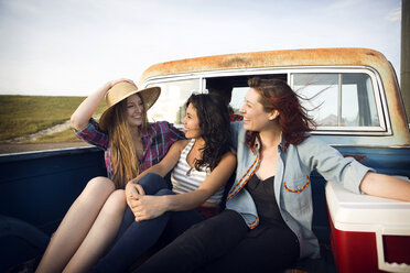 Fröhliche Freunde, die nebeneinander sitzen, während sie nebeneinander in einem Pick-up-Truck fahren - CAVF19160