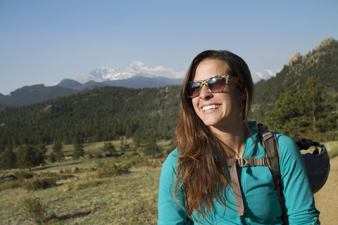 Fröhliche Wanderin, die wegschaut, während sie auf einem Berg steht, lizenzfreies Stockfoto
