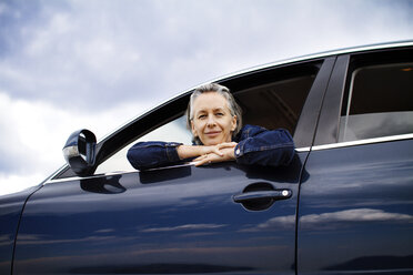 Portrait of woman leaning on car window against sky - CAVF19308