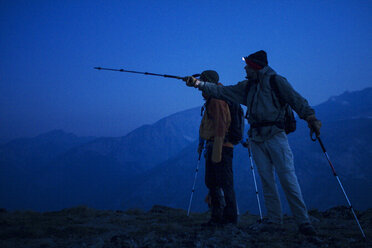 Hiker showing something to friend while standing on mountain - CAVF19328