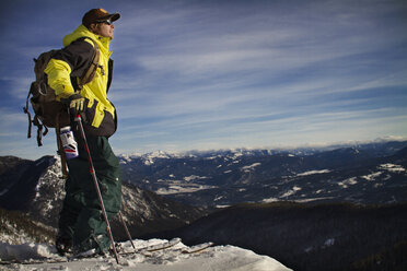 Male backpacker standing on mountain against sky - CAVF19376