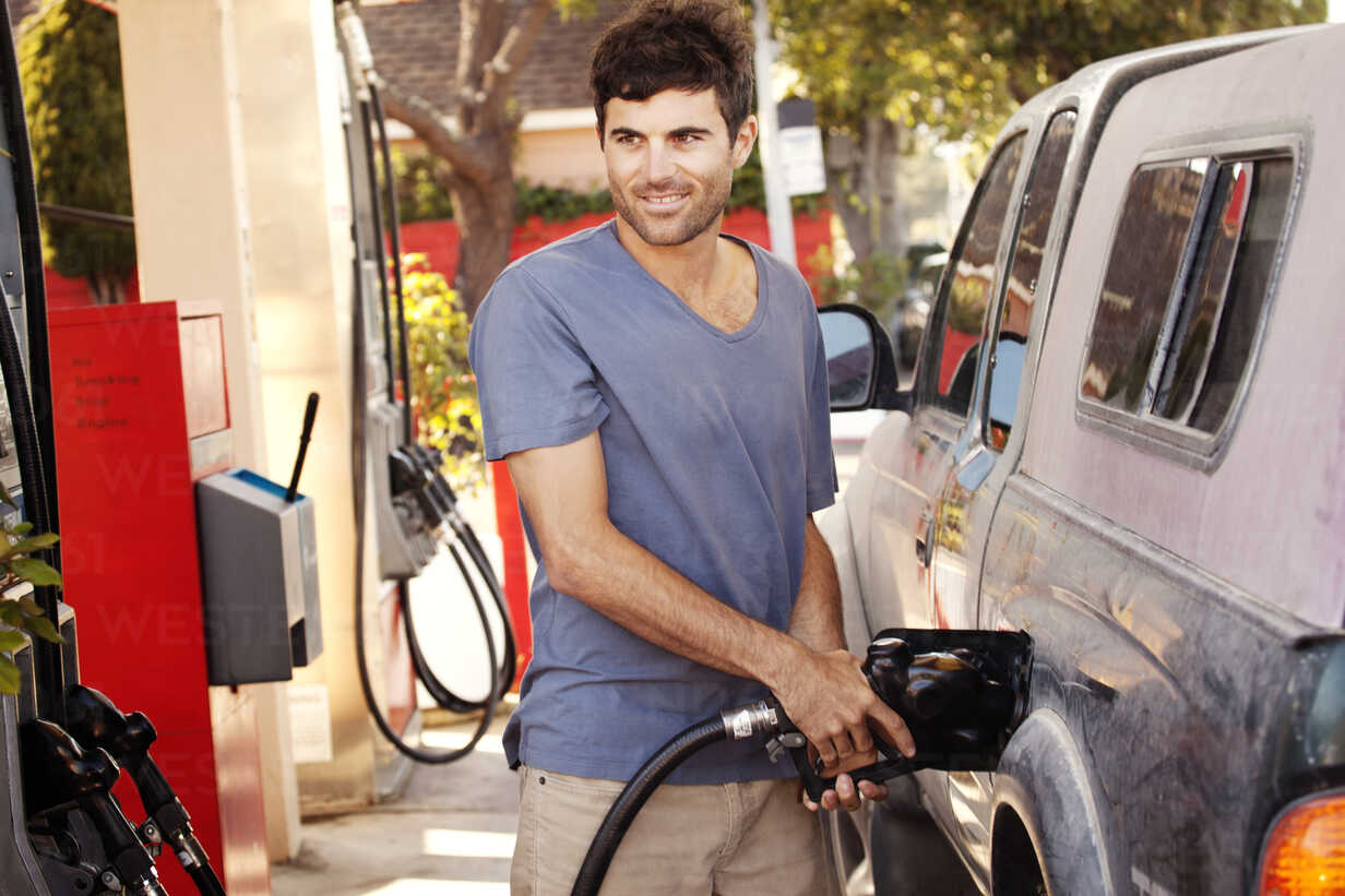 Mann tankt Auto an einer Tankstelle auf, lizenzfreies Stockfoto