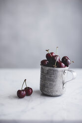 Cherries in metal cup on table - CAVF19488