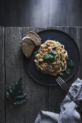 Overhead view of creamy beef and dried tomato fettuccine served with bread in plate on table - CAVF19624