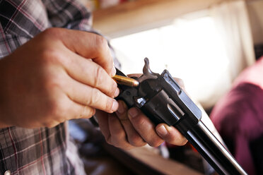 Nahaufnahme der Hände eines Mannes beim Laden eines Revolvers - CAVF19725