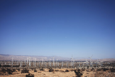 Wind turbines on field against clear blue sky - CAVF19735