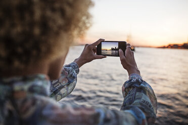 Ausgeschnittenes Bild einer Frau, die mit ihrem Smartphone das Meer fotografiert - CAVF19768