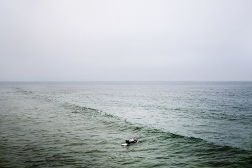 Entfernte Ansicht von Frau Surfen im Meer gegen klaren Himmel - CAVF19811