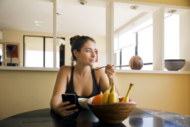 Thoughtful woman eating breakfast on table at home - CAVF19839