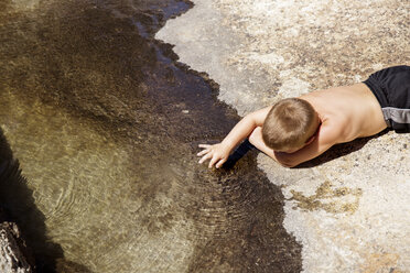 Rückansicht eines Jungen ohne Hemd, der am Seeufer spielt - CAVF19869