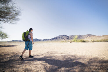 Hiker walking on field against clear blue sky - CAVF19883