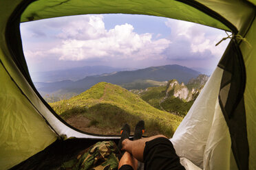 Niedriger Ausschnitt eines Mannes, der in einem Zelt vor Bergen liegt - CAVF19901