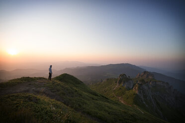 Distant view of hiker standing on mountain against clear sky during sunset - CAVF19907