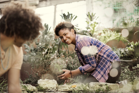 Glückliche Frau sieht ihren Freund bei der Gartenarbeit im Gemeinschaftsgarten an - CAVF19954