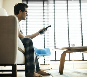 Side view of man watching television at home - CAVF19985