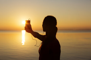 Silhouette einer Frau beim Fotografieren des Horizonts bei Sonnenuntergang - CAVF20033