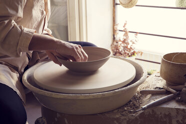 Female potter molding clay on pottery wheel in workshop stock photo