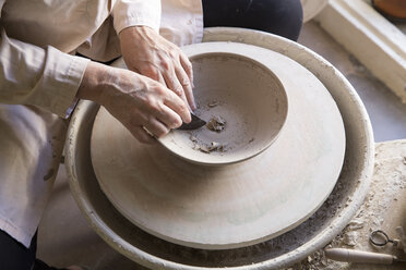 High angle view of woman making pot on pottery wheel - CAVF20108