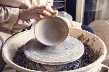 Midsection of woman molding clay in pottery wheel stock photo
