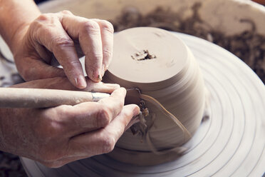 Cropped image of woman molding shape to clay with work tool on pottery wheel - CAVF20115