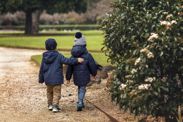 Rückansicht von Brüdern in warmer Kleidung beim Spaziergang im Park - CAVF20156