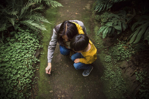 High angle view of mother and son crouching on field at park - CAVF20159