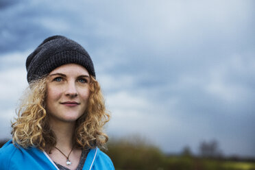 Nachdenkliche Sportlerin mit Blick in die Ferne gegen bewölkten Himmel - CAVF20197