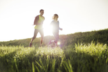 Friends running on grassy field during sunset - CAVF20203