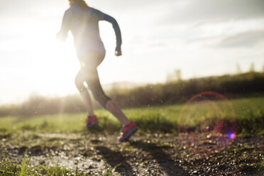 Low section of woman jogging on field during sunset - CAVF20219