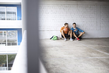 Männliche Freunde mit Basketball und Skateboard auf einem Parkplatz - CAVF20244