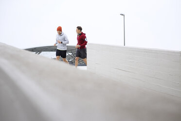 Männliche Freunde joggen auf dem Fußweg am Parkplatz gegen den klaren Himmel - CAVF20247