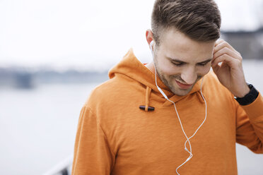 Lächelnder männlicher Sportler hört Musik im Freien - CAVF20257