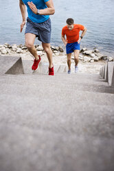 Hohe Winkelansicht von männlichen Athleten, die auf Stufen am Strand laufen - CAVF20269