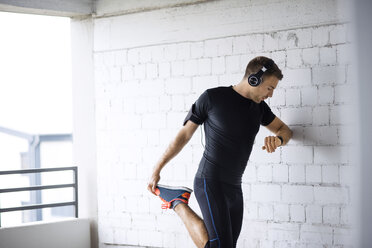 Determined man holding leg while exercising in parking lot - CAVF20281