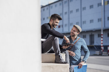 Freunde unterhalten sich mit einem Tablet an einem Gebäude in der Stadt - CAVF20301