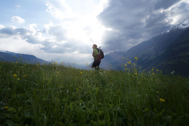 Seitenansicht einer Wanderin, die auf einem Feld gegen einen bewölkten Himmel läuft - CAVF20329