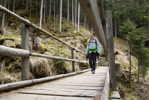 Weibliche Wanderin, die auf dem Holzsteg im Wald spazieren geht - CAVF20333