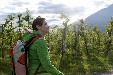 Side view of smiling female hiker on field - CAVF20335