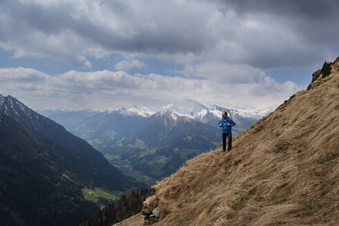 Nachdenklicher männlicher Wanderer auf einem Berg vor bewölktem Himmel stehend - CAVF20338